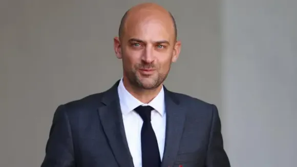 Barrot in a grey suit outside, smiling slightly