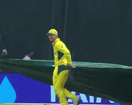 David Warner helps groundsman during rain delay