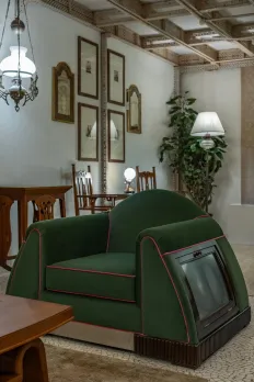 A triangular art deco armchair, part of a sofa set, from the 1940s with a small bookcase tucked under each armrest