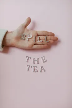 A picture of a hand and silver alphabets spelling out Spill The Tea