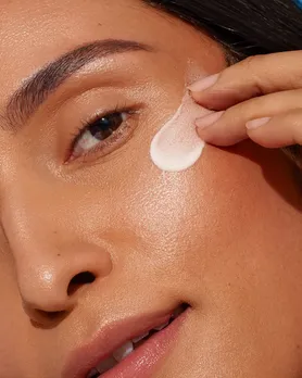 A woman applying sunscreen with SPF 30 on her face