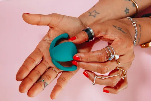 Close-up of tattooed  hands holding a teal  sex toy, representing  India’s growing sex  positivity and sexual  wellness culture