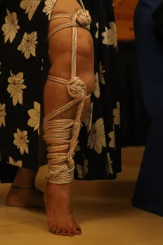 Detailed view of rope  bondage on a person’s leg, showcasing  traditional shibari  knots at an Indian  BDSM community  event