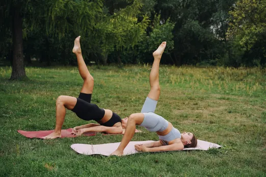 Two women performing yoga to take care of their health and wellness
