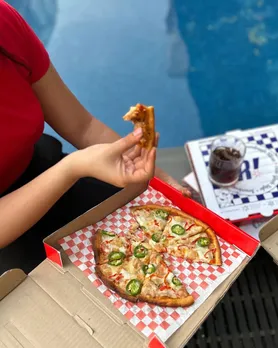 A woman enjoying a slice of fast food pizza in India