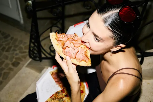 A woman munching on a big slice of pizza in India