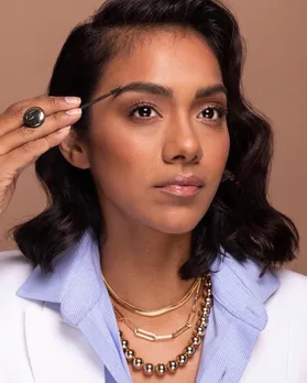 A brown disability consumer in beauty applying brow gel using an adaptive beauty tool