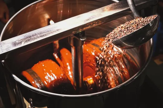 A metal tub with chocolate inside it as Indian cacao beans get added to it to show how chocolate is made by Indian chocolatiers including Pascati