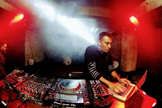 A DJ works on his laptop and the DJ console to show the way DJ culture in India has evolved thanks to AI in music and coffee raves
