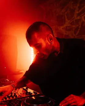 A zoomed in shot of a man wearing earrings and working the DJ console to show the evolving DJ culture in India and the rise of techno in India