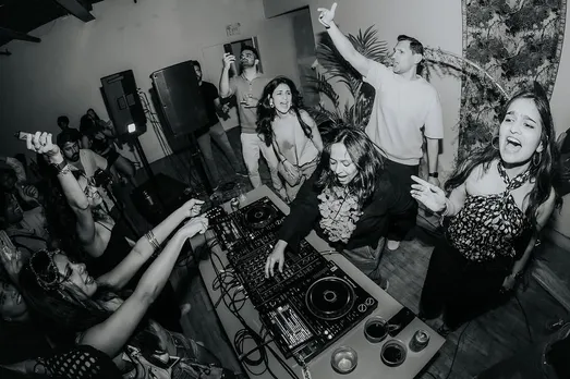 A black and white picture of people dancing in a room as a DJ plays to show female DJs in India are changing the electronic music in India
