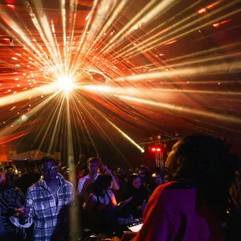 A shot with people dancing to a DJ, who is playing a set with some great visual and lighting work, to show the evolving DJ culture in India and music festivals in India catering to just electronic music in India