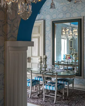 A picture of a royal dining space, complete with a chandelier reflected in a mirror to show how luxury boutique hotels in India are also heritage.