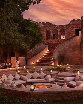 A picture of seating around a firepit inside a Fort, with a well-lit path leading up to thw steps, to show how luxury boutique hotels in India make for the best boutique hotels monsoon India.