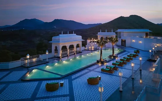 A zoomed out shot of a pool in a heritage resort with lighting around it, with a view overlooking the hills, to show how heritage boutique hotels India make for the best boutique hotels monsoon India