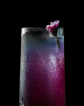 A purple drink with a minimal, small flower as garnish to show the popularity  of Japanese spirits India including the introduction of the Izakaya bar in India