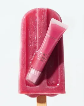 A lip gloss from Lancôme placed on an ice candy hinting the retro revival beauty industry trend