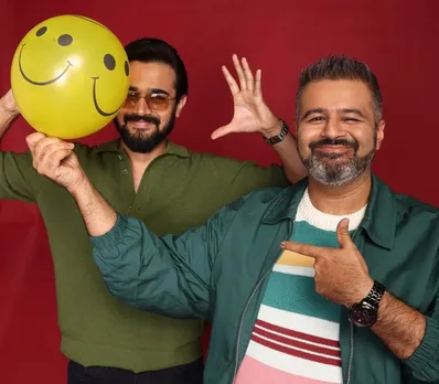 A man poses with a balloon with a smiling face on it, while another poses behind it to depict how some of the best podcasts India are also about mental health