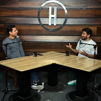 Two men sit at a table with mics and chat to show the evolution on podcasts in India that have led to best podcasts India