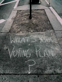 A street artwork with the words 'what's you voting plan' to show how politics and dating in India are coming together as well as the importance of different political ideologies dating.