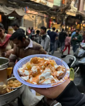 An image of a kachodi being served on the street side, with chutneys on top, to show how this India street food Jaipur is one of the more famous Indian snacks globally.