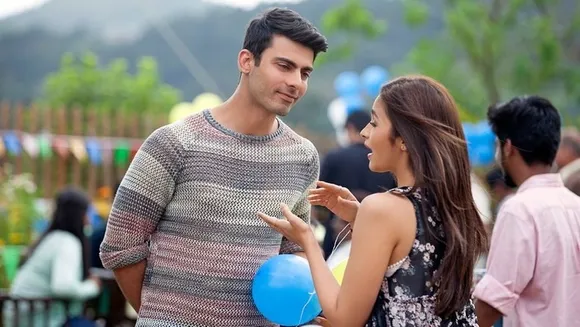A woman talks animatedly to a man listening attentively while at an outdoor event to show how straight women and gay men friendship work and how the gay best friend trope is represented in India