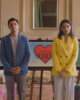 A man and a woman stand in front of a placard that reads 'Made in  Heaven' to depict the evolution of the gay best friend trope and queer representation in pop culture moving on from LGBTQ+ stereotypes in media.