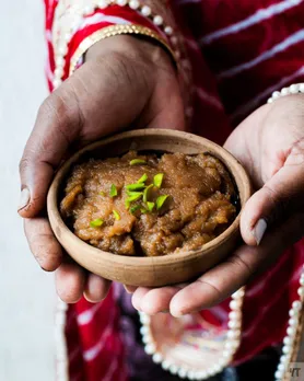 A picture of a woman holding a earthen bowl of kada prasad in her hands, an essential part of  Punjabi food history and Punjabi cuisine, being one of the most recognisable Punjabi dishes in the world that is authentic in preparation