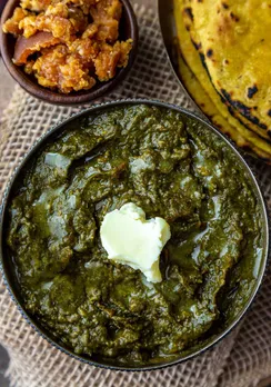 A picture of  sarson ka saag with some pickles and missi roti, the two crucial dishes of Punjabi cuisine in India and authentic Punjabi cuisine, which have made their mark in Punjabi food history