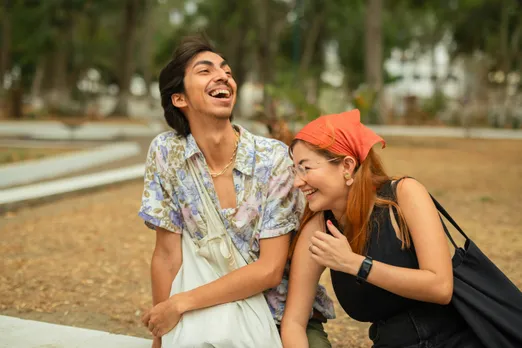 A picture of a man and a woman sitting and laughing in a park to show how queer dating in India is different in the aspect of staying friends with exes