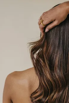 A backshot of a woman's touching her wavy hair