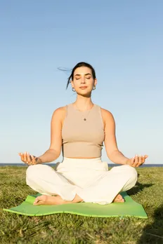 A woman practising yoga in an open landscape to combat stress and periods