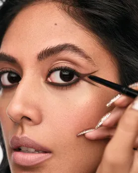 A woman applying a brown Kajal pencil