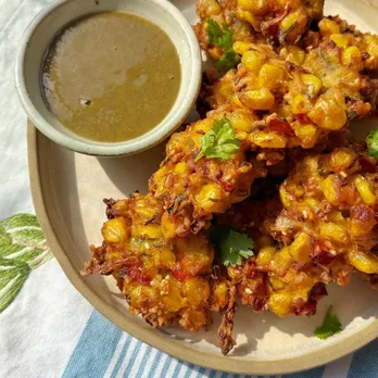 A picture of a dish with a bowl of indian condiments like chutneys to accompany it