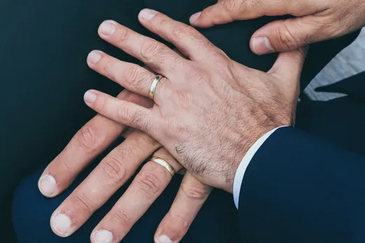 A picture of two male hands wearing rings on their wedding ring finger to show how queer parenthood legal rights and queer parenting in India are becoming a reality despite hurdles
