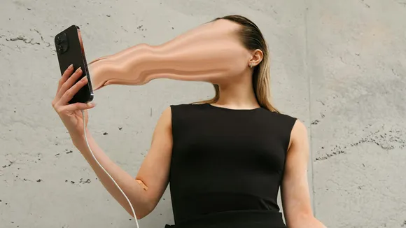 A picture of a woman holding a phone with her face going into the screen to depict how online outrage culture feeds off attention marketing and rage baiting in marketing