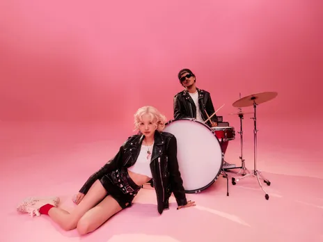 A picture of a female vocalist sitting and a man playing the drums to depict the global popularity as well as the popularity of Asian influence in India