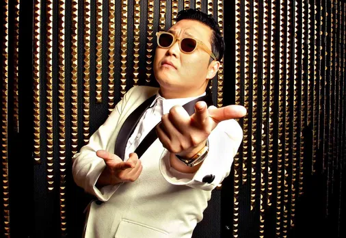 A man wearing a white suit and black shades poses for the camera, to depict the popularity of K-Pop in India via Psy's Gangnam Style to show how Asian influence in India is everywhere