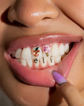 A picture of a woman's teeth, with elf encrusted on them, suggesting how hype marketing works in the beauty industry in India