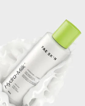 A bottle of milky toner splashed into a bowl of milk