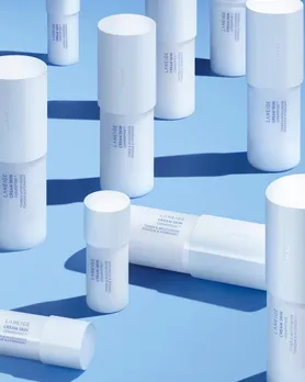 A few bottles of Laneige milky toners placed on a powder blue backdrop