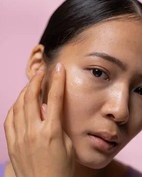 A woman applying a gel-based non foaming cleanser on her cheeks