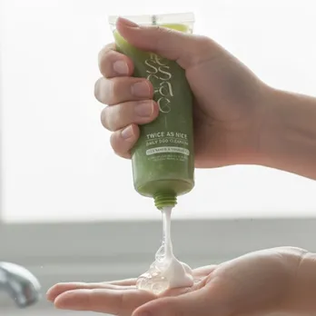 A person squeezing out non foaming cleanser from a green tube in her hands