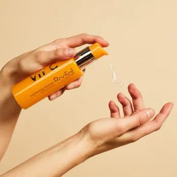 A non foaming cleanser dispensing from an orange bottle onto the model's hand