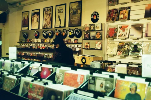 A picture of a woman browsing through vinyl records at a vinyl record store to show the growing popularity of vinyl records in India especially the growing connection between youth and vinyl records that's leading to community spaces India music