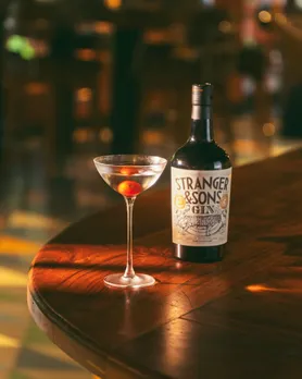 A bottle of Stranger & Sons Gin places next to a glass of a martini to show how Indian craft gins, including flavoured Indian gin, are gaining consumers worldwide