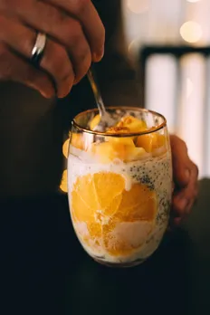 A tall glass of chia pudding down with mangoes and oranges for a high-fibre diet