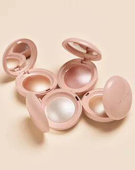 Four shades of highlighter powder from Rare Beauty by Selena Gomez on a white table