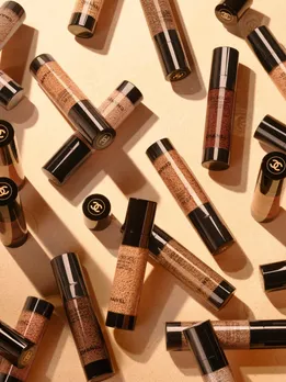 A few bottles of Chanel Les Beiges skin tint placed on a flesh-toned backdrop