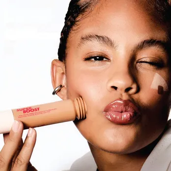 A female model pressing a tube of the skin tint against her cheek